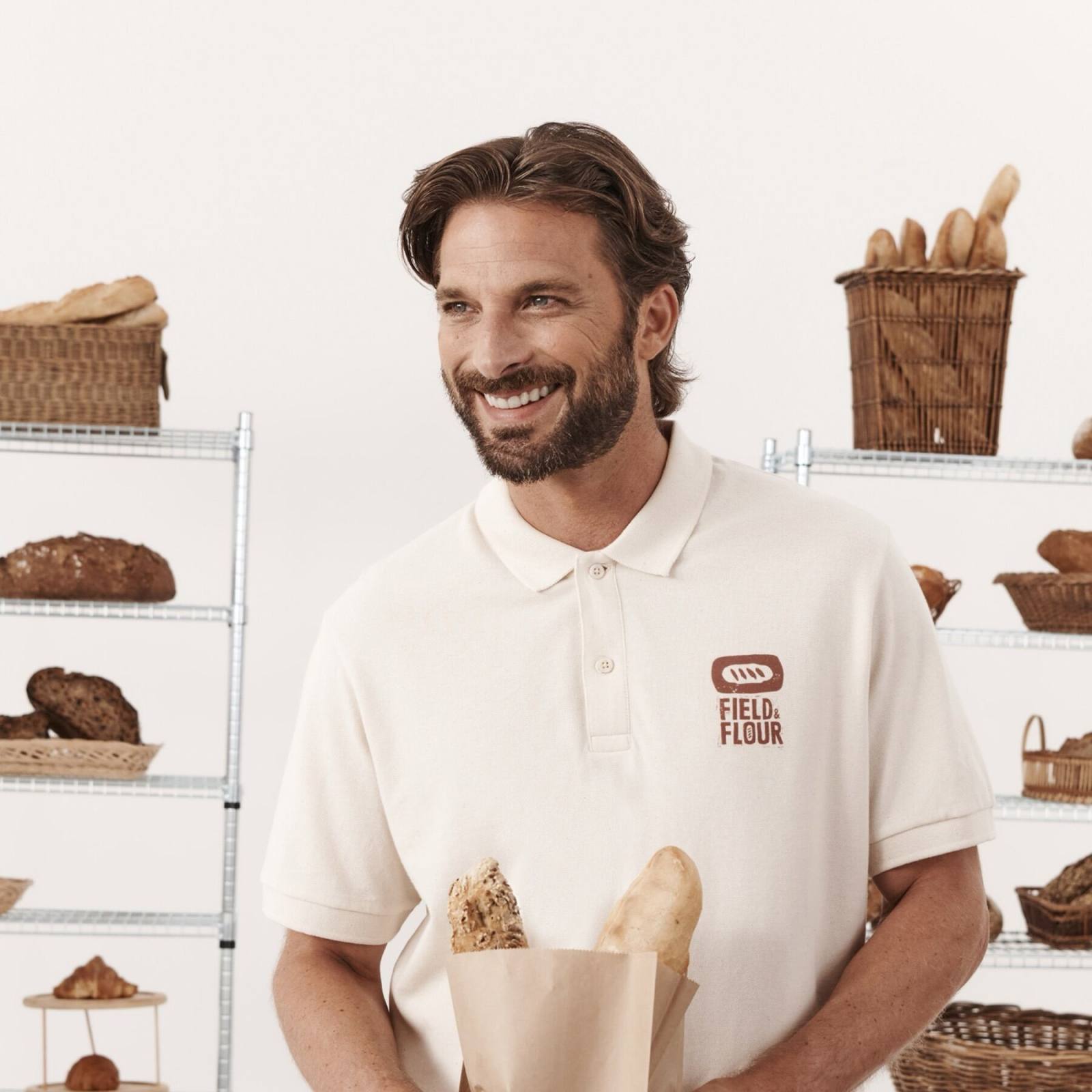 Bäcker im cremefarbenen Poloshirt mit Firmenlogo auf der Brust
